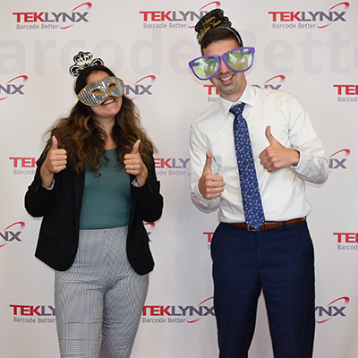 Two TEKLYNX employees during new years party in front of barcode better backdrop